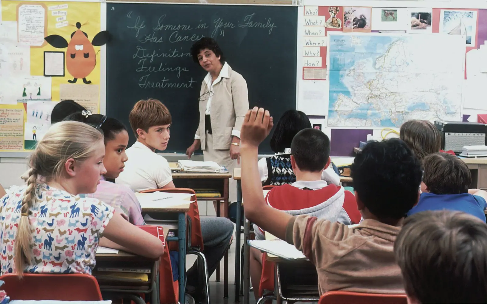 A teacher at the board in front of a classroom of children