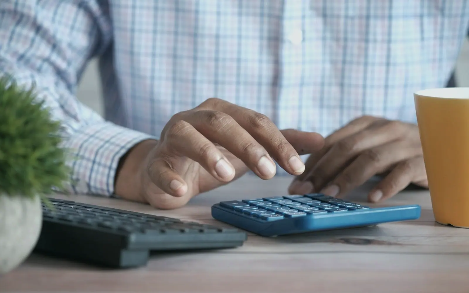 Hands working a calculator beside a keyboard
