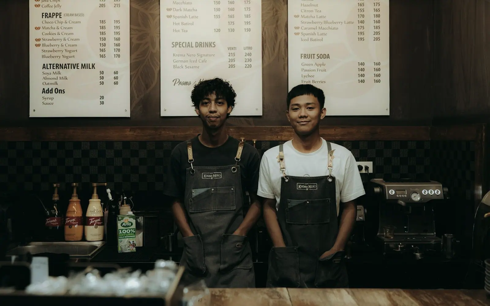 Two baristas smiling behind a café counter