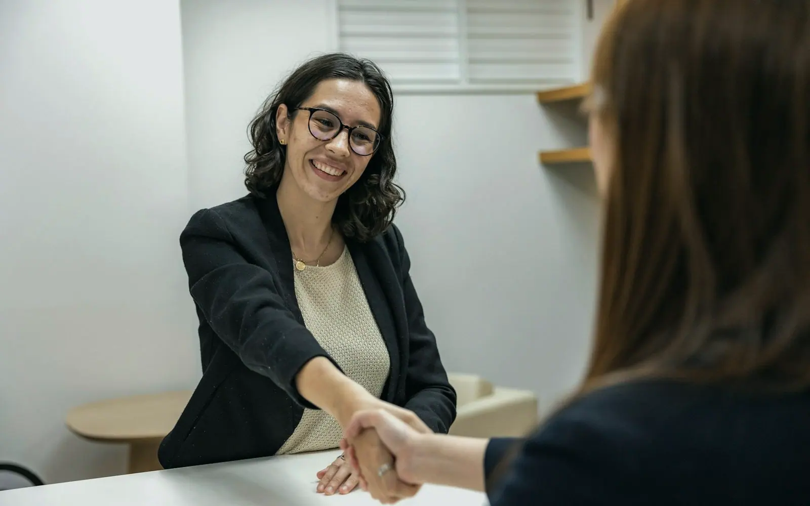 A recruiter shaking hands with a candidate across an interview table