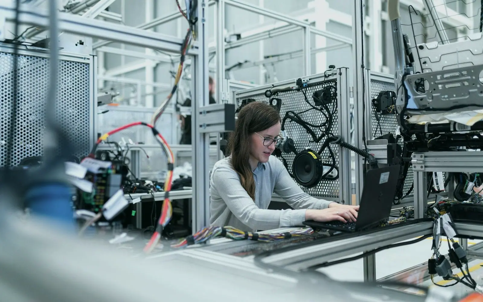 An engineer working on a laptop beside an automated production line